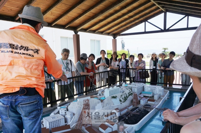 다카시마 석탄자료관의 하시마 모형 앞에서 설명을 듣고 있는 많은 관광객들. 유네스코 문화유산 등재후 현재 관광섬으로만 부각되고 있는 모습이다.