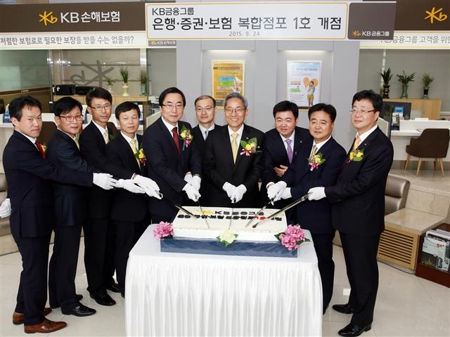 윤종규(오른쪽 세 번째) KB금융 회장이 24일 복합점포 1호 입점식에서 김정기(왼쪽 첫 번째) KB국민은행 전무 등과 함께 케이크를 자르고 있다.