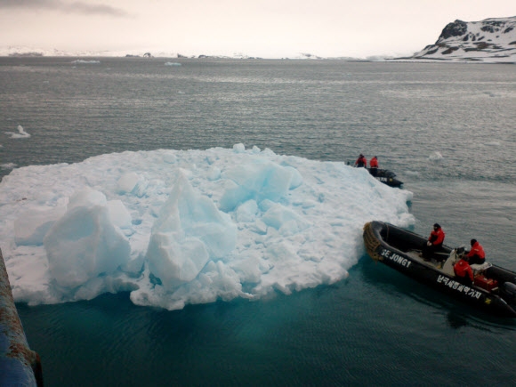 이기영(아래 보트 오른쪽) 해군 상사가 지난해 12월 남극 킹 조지섬 앞바다에서 세종과학기지 동료 대원들과 함께 고무보트로 화물선에 부딪힌 유빙을 밀어내고 있다. 해군 제공