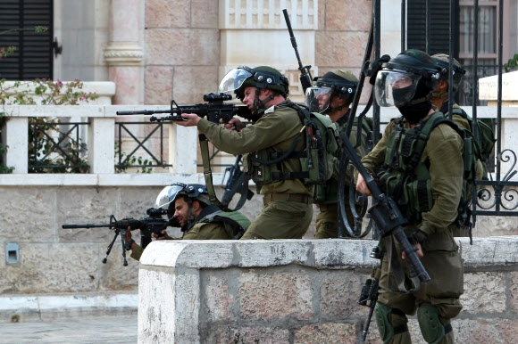 12일(현지시간) 서안의 베들레헴에서 이스라엘 군인들이 팔레스타인 시위대를 향해 총을 겨누고 있다. 베들레헴 AFP 연합뉴스