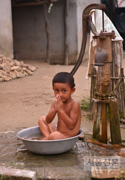 세숫대야에서 목욕을 하면서도 외지인만 보면 나마스테라고 인사를 하는 치트완 타루족 아이.