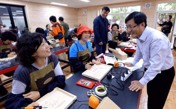 김성환(오른쪽) 노원구청장이 22일 공릉동에 문을 연 ‘목공예 체험장’을 찾아 체험하는 주민들과 웃으며 이야기를 나누고 있다.  이언탁 기자 utl@seoul.co.kr