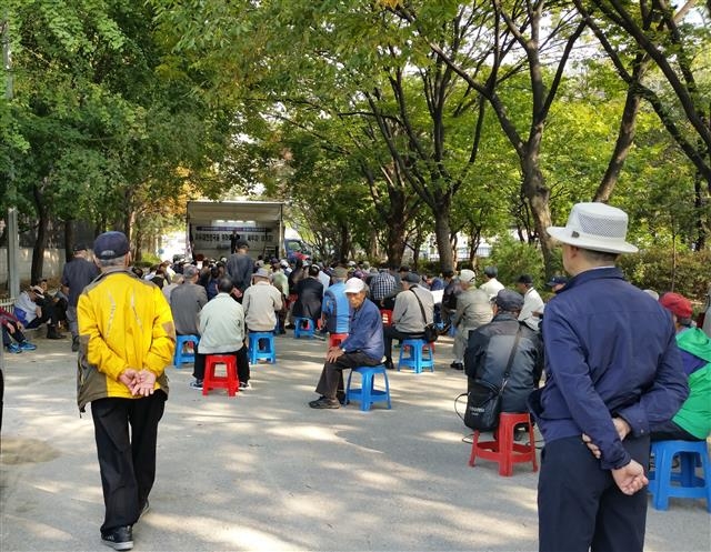 종묘광장 공터의 연설차량 앞 플라스틱 의자에 노인들이 자리를 잡고 앉아 있다.