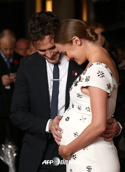 영국 배우 샘 클라플린이 5일(현지시간) 런던 중심부에서 열린 영화 ‘헝거게임: 더 파이널(The Hunger Games: Mockingjay Part 2)’ UK 시사회에 참석해 임신한 아내 영국 여배우 로라 하드독의 배에 손을 얹고 아기에게 인사하고 있다.     ⓒ AFPBBNews=News1