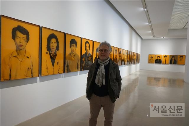 굴곡진 현대사를 견뎌 온 평범한 사람들의 이야기를 강렬한 화법으로 전달해 온 화가 안창홍이 아라리오갤러리 천안의 전시장에서 자신의 작품 ‘49인의 명상’을 배경으로 포즈를 취하고 있다.