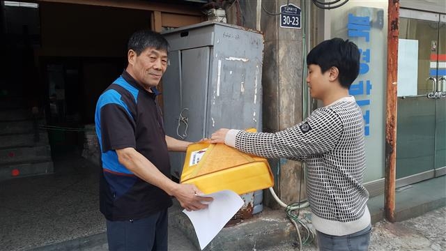 동대문구 사회복지협의회 관계자가 오랫동안 고향을 방문하지 못한 쪽방촌 주민에게 고향에 내려갈 기차표와 선물을 전달하고 있다. 동대문구 제공