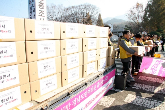‘홍준표 경남도지사 주민소환운동본부’가 30일 경남도청 정문 앞에서 트럭에 싣고 온 서명부를 제출하기 전 기자회견을 하고 있다.  창원 연합뉴스 