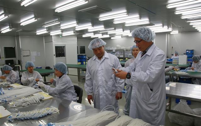 김영만(왼쪽 네 번째) 옥천군수가 지난달 23일 의료기기 단지에 입주해 있는 에이스메디컬에서 방진복을 입고 생산현장을 둘러보고 있다. 옥천군 제공