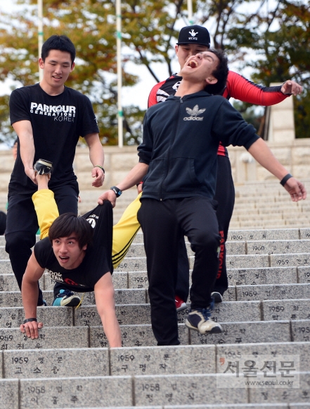 서울 서대문구 연세대학교 노천극장에서 오로지 팔을 이용해 계단을 내려오는 훈련을 하는 사람을 위해 몸을 잡아주던 학생이 힘겨움에 소리지르고 있다.