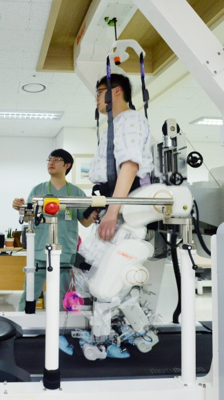 군에서 입은 사고로 몸의 오른쪽이 마비된 오창주(35)씨가 재활센터 로봇치료실에서 보행재활로봇을 이용해 바른 자세로 걸을 수 있도록 반복 학습시키는 보행치료를 받고 있다.