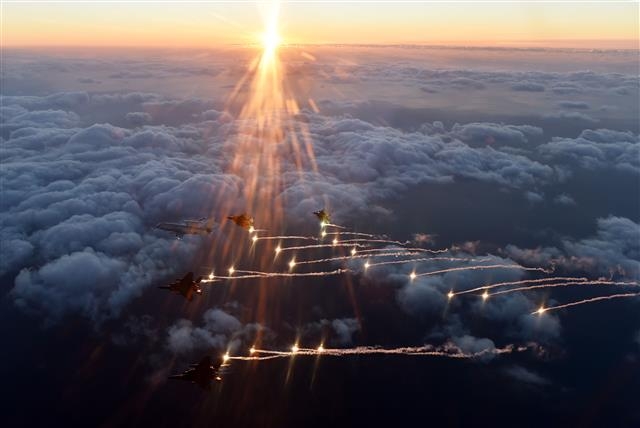 플레어 발사  공군 11전투비행단 소속 F15K 편대와 E737 조기경보기 ‘피스아이’(선두)가 31일 동해 상공에서 태양을 배경으로 플레어를 발사하며 기동하고 있다. 공군 제공
