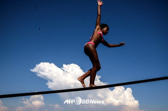 한 소녀가 26일(현지시간) 브라질 리우데자네이루 과나바라 만에서 보트의 무어링 벨트 위를 걷기위해 균형을 잡으려 애쓰고 있다. ⓒ AFPBBNews=News1