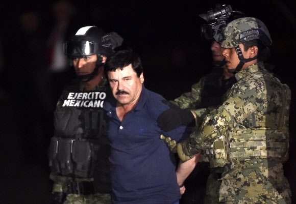 8일 고향에서 붙잡힌 구스만(가운데)이 멕시코시티 공항에서 수갑에 묶인 채 호송되고 있다. 멕시코시티 AFP 연합뉴스