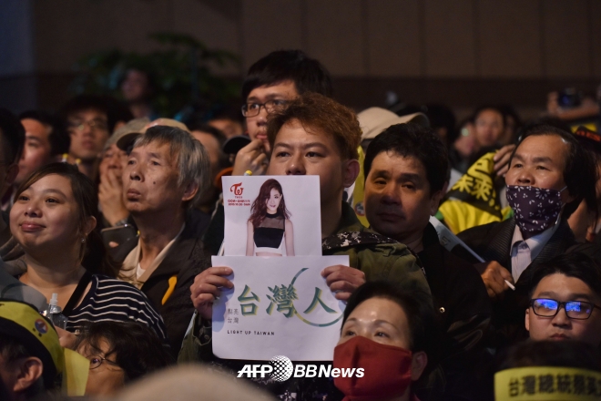 대만 민진당(DPP) 지지자가 대만 국기를 흔들어 논란이 된 쯔위의 사진을 들어보이고 있다. ⓒAFPBBNews=News1