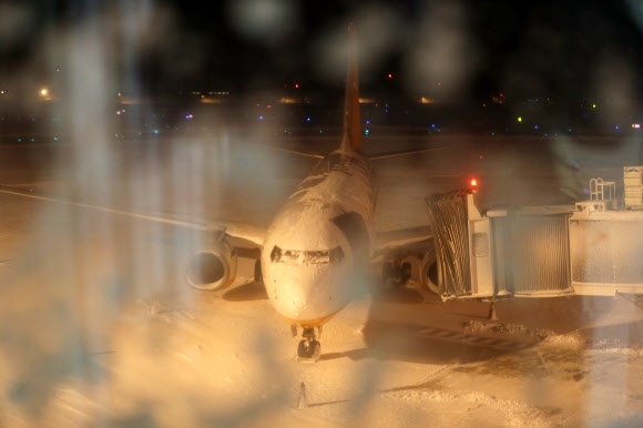 한파가 몰아친 23일 제주공항 활주로에 많은 눈이 쌓이면서 오후 5시 50분부터 운영이 잠정 중단됐다. 이날 운항을 하려던 항공기가 기체에 눈이 쌓인 채 멈춰 서 있다.  연합뉴스