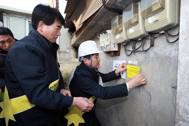 김영배(오른쪽) 성북구청장이 건물의 갈라진 틈에 ‘균열폭 측정기’와 담당직원 연락처를 붙이고 있다. 성북구 제공