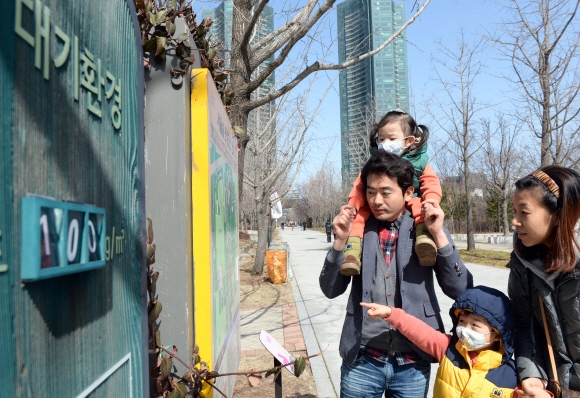 올봄 처음 황사주의보가 내려진 6일 성동구 서울숲 공원에 어린 자녀에게 마스크를 착용케하고 나들이 나온 가족이 미세먼지농도 표지판 옆을 지나고 있다.  2016.03.06 강성남 선임기자 snk@seoul.co.kr