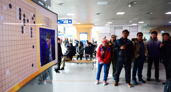 이세돌 9단과 구글 인공지능(AI) 바둑프로그램 알파고의 세기의 대결이 시작된 9일 시민들이 서울역 대합실에서 텔레비전 중계를 지켜보고 있다.  박윤슬 기자 seul@seoul.co.kr