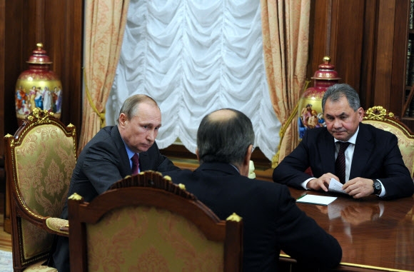 블라디미르 푸틴(왼쪽) 러시아 대통령이 14일(현지시간) 모스크바의 크렘린에서 세르게이 쇼이구(오른쪽) 국방장관, 세르게이 라브로프 외무장관과 심각한 표정으로 의견을 교환하고 있다.  모스크바 AP 연합뉴스