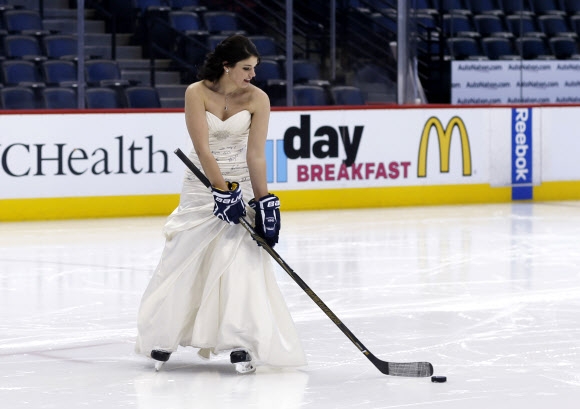 3일(현지시간) 미국 콜로라도주 덴버에서 북미아이스하키리그(NHL) 콜로라도 애벌랜치와 세인트루이스 블루스의 경기 시작되기 전 아이스링크에서 결혼식을 올린 한 신부가 퍽을 드리블하고 있다. AP 연합뉴스