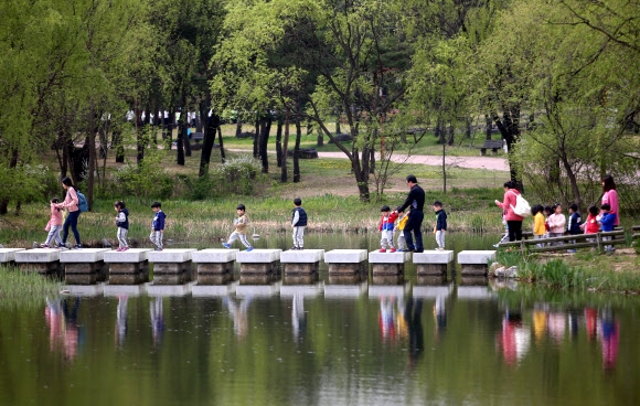 서울 마포구 월드컵공원에서 어린이들이 완연한 봄 날씨 속에 돌다리를 건너고 있다.  연합뉴스 