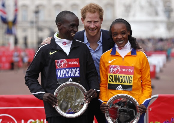 24일 런던마라톤 남자 엘리트 우승자 엘리우드 킵초게(왼쪽)와 여자 엘리트 우승자 제미마 숨공(오른쪽)이 영국 해리 왕자로부터 축하를 받은 뒤 포즈를 취하고 있다.  런던 로이터 연합뉴스