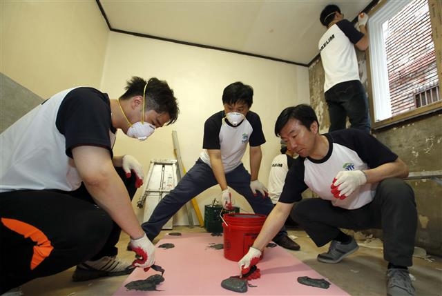 지난해 실시한 대림산업의 ‘사랑의 집고치기’ 활동에서 김한기(앞줄 오른쪽) 대림산업 건축사업본부장이 직원들과 내벽 단열 작업을 하고 있다. 대림산업 제공