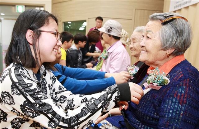 어버이날을 하루 앞둔 지난 7일 아시아나항공 임직원 자녀들이 서울 강서구 등촌4종합사회복지관에서 진행한 ‘사랑의 카네이션’ 행사에서 독거 노인의 가슴에 카네이션을 달아 드리고 있다. 아시아나항공 제공