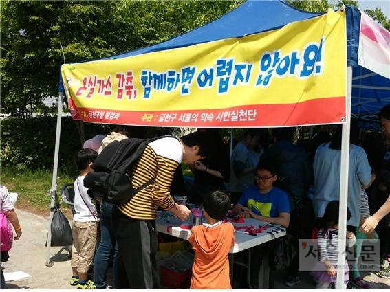 지난 어린이날 서울 금천구청에서 진행한 행사에서 한 여성이 아이와 함께 에코마일리지 가입 신청서를 쓰고 있다. 금천구 제공 