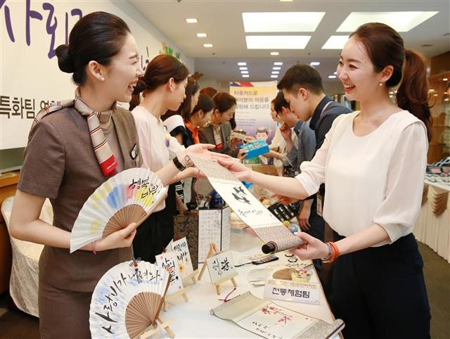 2일 서울 강서구에서 열린 ‘2016 캐빈 사회공헌바자회’에서 아시아나항공 승무원들이 판매 물품을 들고 웃으며 기념사진을 찍고 있다.