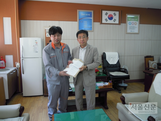 충북 청주에서 자동차 정비공으로 일하는 송한영(왼쪽)씨가 괴산고 전원태 교장에게 장학금 3000만원을 전달하고 있다. 충북도교육청 제공 