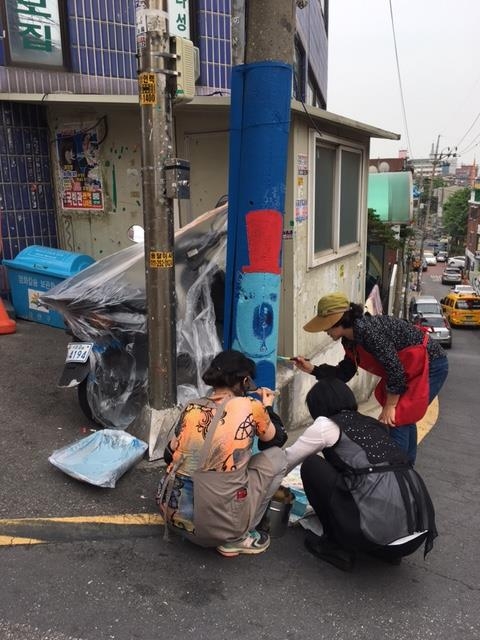 ‘꿈꾸는 마을공방 여우랑’ 회원들이 동네 주민들과 어울려 전신주에 동물 그림 그리기 작업을 하고 있다. 금천구 제공