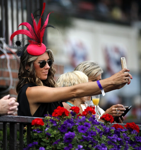 11일(현지시간) 미국 뉴욕주 엘몬트에서 열린 ‘제148회 벨몬트 스테이크스 경주대회(Belmont Stakes)’ 에 특이한 모자를 쓴 관람객이 스마트폰으로 사진을 찍고 있다. AP 연합뉴스