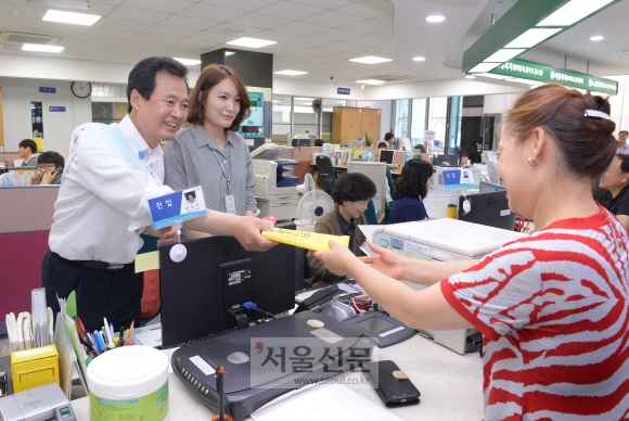박겸수(왼쪽) 서울 강북구청장이 지난 13일 미아동 주민센터에서 일일 동장으로 일하며 주민에게 민원 서류를 발급해 주고 있다. 최해국 기자 seaworld@seoul.co.kr