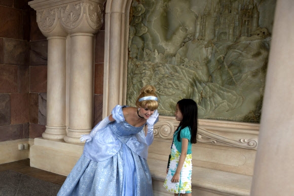 중국 상하이 디즈니랜드 개장을 하루 앞둔 15일(현지시간) 디즈니 캐릭터 의상을 입은 여성과 한 중국인 소녀가 얘기를 나누고 있다. AP 연합뉴스