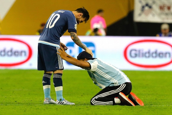 아르헨티나 대표팀의 리오넬 메시(왼쪽)가 22일 코파 아메리카 센테나리오 미국과의 준결승 후반 시작 직전 그라운드에 난입해 자신을 신으로 경배하는 듯한 제스처를 취하는 팬을 달래고 있다. 휴스턴 EPA 연합뉴스