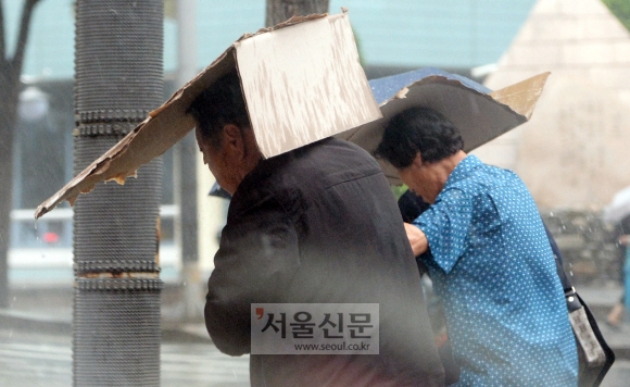 소나기가 쏟아진  22일 서울정부청사 근처에서 우산을 준비하지 못한 시민들이 박스를 우산 삼아 쓰고 걷고 있다. 박윤슬 기자 seul@seoul.co.kr