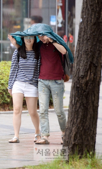 소나기가 쏟아진  22일 서울 종로구 세종문화회관 근처에서 한 남녀가 겉옷을 우산 삼아 함께 쓰고 걷고 있다. 박윤슬 기자 seul@seoul.co.kr