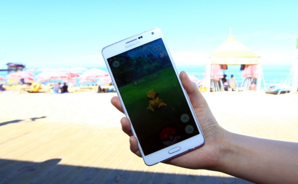 속초해변에서 실행된 포켓몬 고 게임에 등장한 포켓몬이 휴대전화 화면에 나타나 있다.  연합뉴스 자료사진