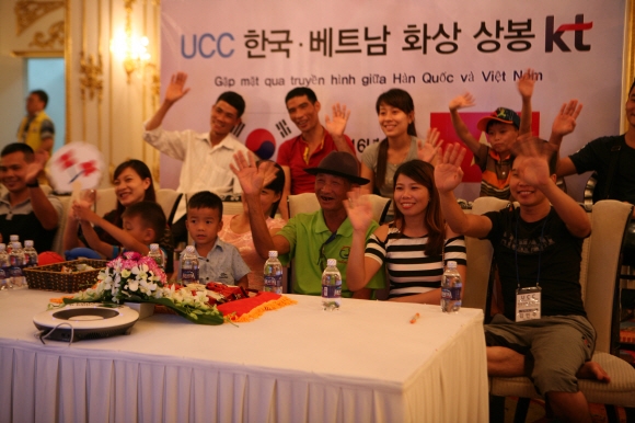 KT 등이 21일 베트남 하노이 그랜드호텔에서 개최한 ‘결혼이주 여성 가족 초청 화상상봉 행사’에서 현지인들이 한국에 시집간 가족에게 손을 흔들며 인사하고 있다. KT 제공