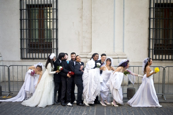 턱시도와 드레스를 각각 차려입은 남녀 공연자들이 21일(현지시간) 칠레 산티아고의 모네다 궁전 앞에서 공연 “Ex-centric”를 알리기 위한 퍼포먼스를 하고 있다. 이 공연은 동성 결혼과 양성평등을 지지하기 위한 쇼로 기획됐다.  AP 연합뉴스