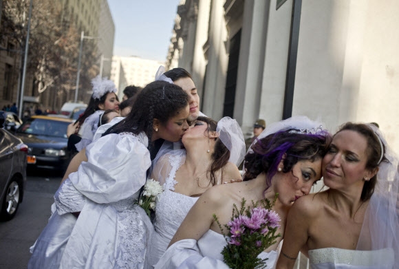 턱시도와 드레스를 각각 차려입은 남녀 공연자들이 21일(현지시간) 칠레 산티아고의 모네다 궁전 앞에서 공연 “Ex-centric”를 알리기 위한 퍼포먼스를 하고 있다. 이 공연은 동성 결혼과 양성평등을 지지하기 위한 쇼로 기획됐다.  AP 연합뉴스 