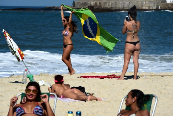 1일(현지시간) 브라질 코파카바나 해변에서 비키니를 입은 여성이 브라질 국기를 들고 한가로운 시간을 보내고 있다. AFP 연합뉴스
