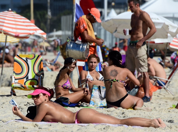 1일(현지시간) 브라질 코파카바나 해변에서 비키니를 입은 여성들이 일광욕을 즐기며 한가로운 시간을 보내고 있다. AFP 연합뉴스