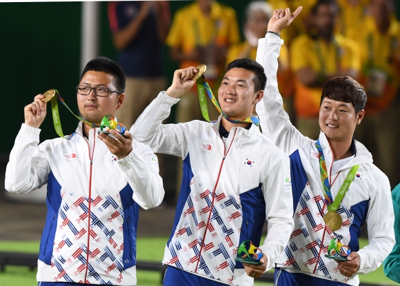 한국에 첫 금메달을 안긴 남자양궁 ‘삼총사’ 김우진(왼쪽부터), 구본찬, 이승윤이 지난 6일(현지시간) 브라질 리우데자네이루 마라카낭 삼보드로무 경기장에서 열린 리우올림픽 양궁 남자 단체전 시상식에서 시상대 가장 높은 곳에 올라 금메달을 들어 보이며 기뻐하고 있다. 리우데자네이루 올림픽사진공동취재단