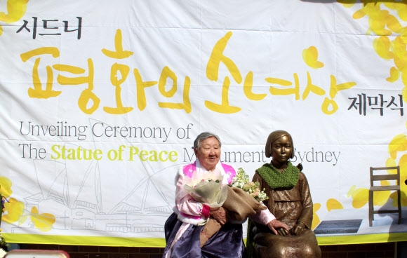 일본군 위안부 피해자 길원옥 할머니가 지난 6일 호주 시드니 한인회관에서 열린 평화의 소녀상 제막식에 참석해 소녀상 옆에 나란히 앉아 소녀의 손을 잡고 있다. 시드니 연합뉴스