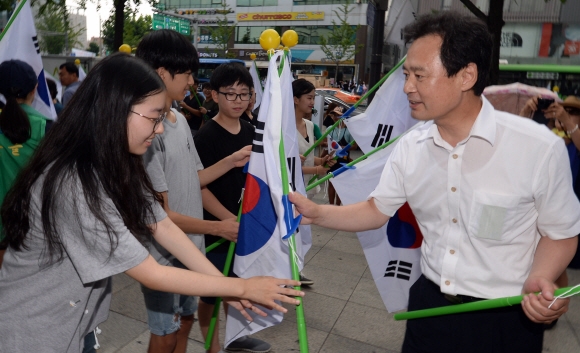 박겸수(오른쪽) 서울 강북구청장이 12일 강북구청 사거리에서 열린 ‘광복절 나라사랑 태극기 달기 행사’에서 지나가는 학생들에게 태극기를 나눠 주고 있다. 박지환 기자 popocar@seoul.co.kr