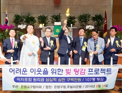 김우영(오른쪽 네 번째) 은평구청장이 지난 14일 은평구의 한 교회에서 열린 ‘빚 탕감 프로젝트’ 행사에서 사들인 부실채권을 불태워 날리고 있다.