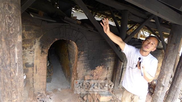 온타야키 마을의 도예가 사카모토 코지가 마을 공동가마에서 장작불로 굽는 도자기들에 대해 설명하고 있다.