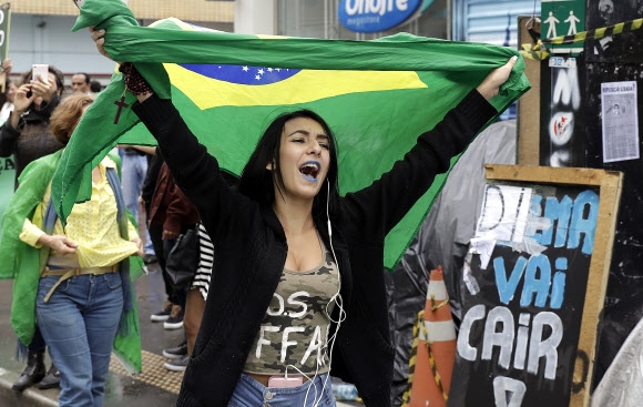 한 여성이 31일(현지시간) 브라질 상파울루에서 브라질 대통령 지우마 호세프의 탄핵을 축하하며 브라질 국기를 흔들며 걷고 있다. AP 연합뉴스